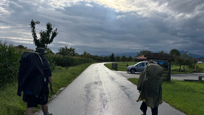 Zwei Pilger in Regenkleidung unterwegs bei bedecktem Himmel.