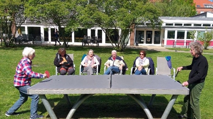 Eine Gruppe von Menschen spielt um einen großen Picknicktisch im Freien.