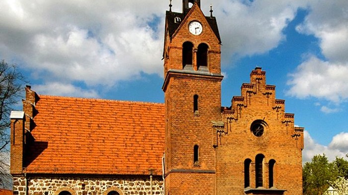 Ein rotes Backsteingebäude mit einem hohen Turm und einem Ziegeldach.