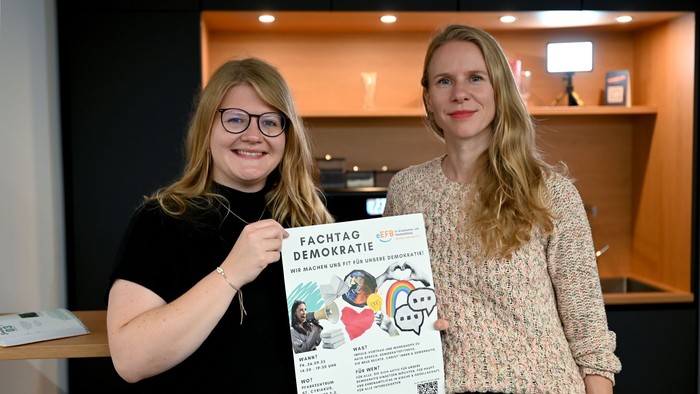 Zwei Frauen halten ein Plakat mit dem Titel 