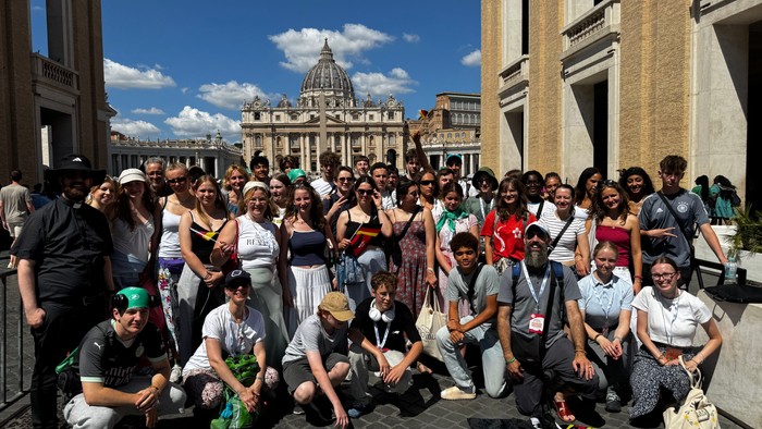 Große Gruppe von Menschen vor dem Petersdom in Rom posiert für ein Foto