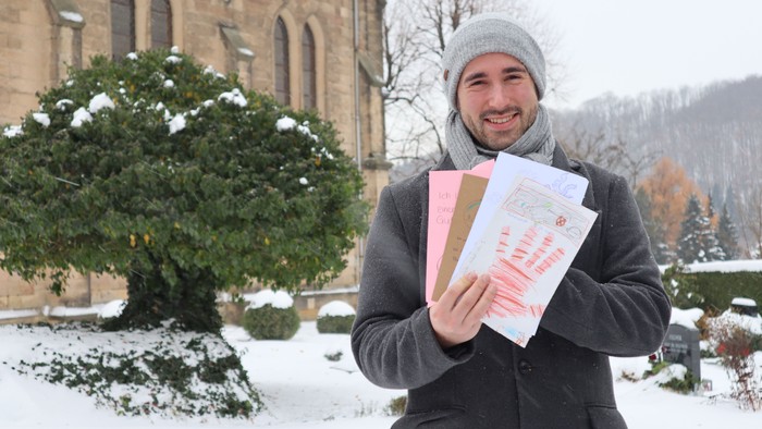 Mann hält Bücher im Schnee vor Kirche