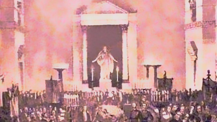 En stor forsamling af mennesker i et indendørs arena med en person på scenen