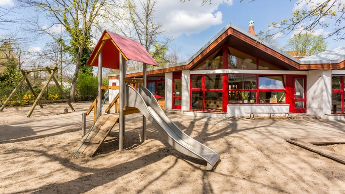 Im Garten befindet sich ein Spielplatz mit Rutsche vor einem Holzhaus.