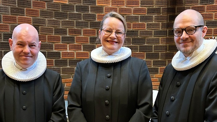 Tre præster står sammen i kirke.