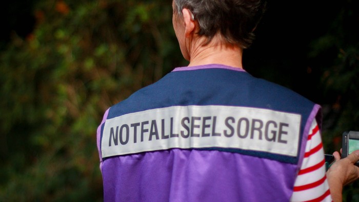 Eine Notfallseelsorgerin mit Uniformsweste und Pieper von hinten
