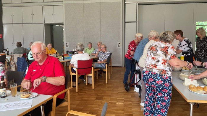 Viele Seniorinnen und Senioren sitzen im blick-punkt an den Tischen um gemeinsam zu essen.