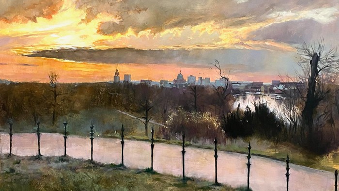 Ein Sonnenuntergang über einer Stadt mit einem Fluss und einem schwarzen Zaun im Vordergrund
