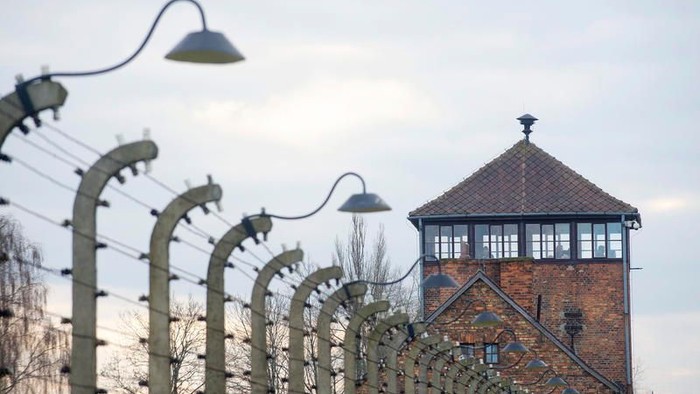 Ein Ziegelgebäude mit Turm und Stacheldrahtzaun im Vordergrund