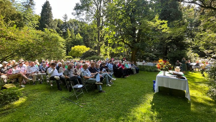 Das Bild zeigt viele der 188 Besucher und Besucherinnen, die im Botanischen Garten auf Stühlen Platz gefunden haben.