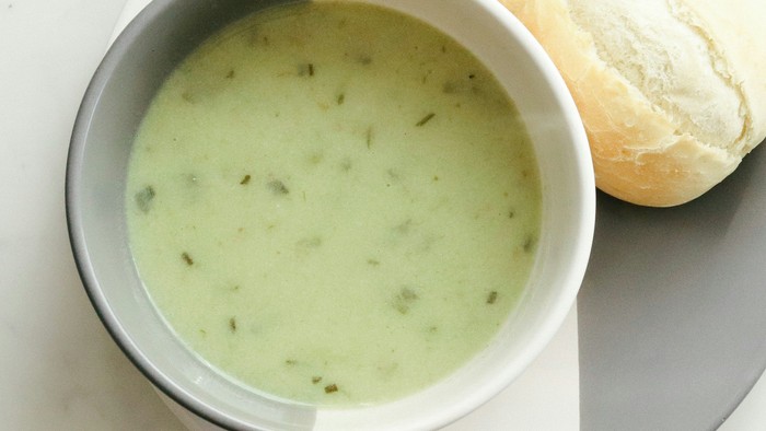 Eine Schale Suppe und ein Brötchen auf einem Teller