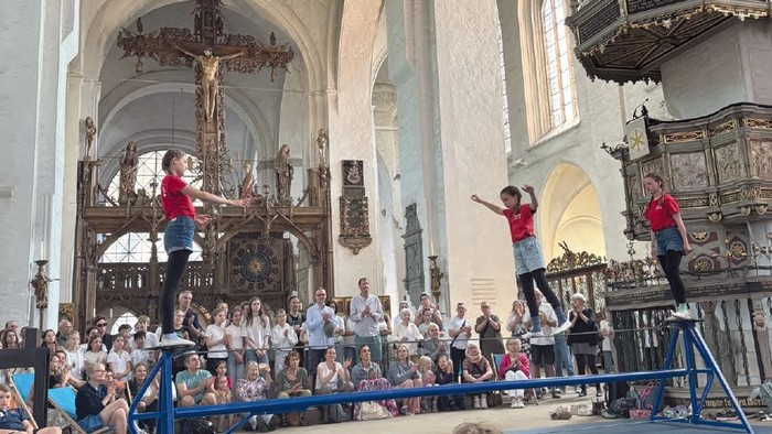 Zirkusartisten performen auf dem Hochseil in einer Kirche vor Publikum