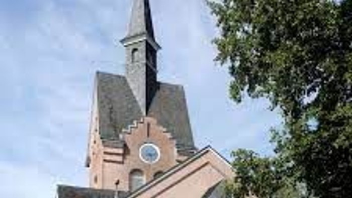 Ein rosa Kirchengebäude mit hohem Turm und Uhr.