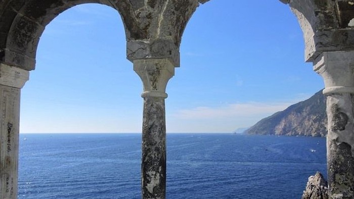 Blick durch Steinbogen auf weites Meer unter klarem Himmel