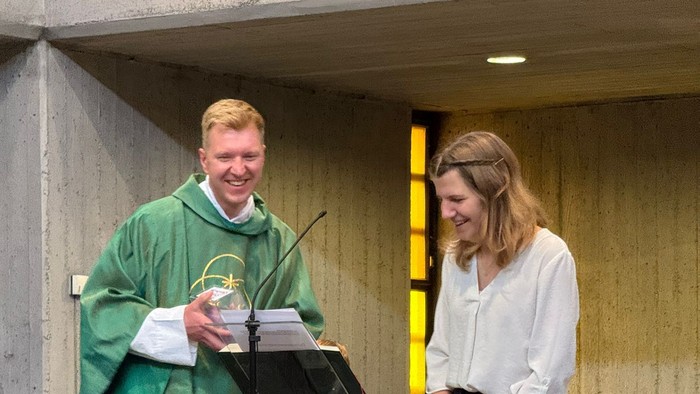 Mann in grüner Robe hält Pokal, Frau in Weiß steht daneben