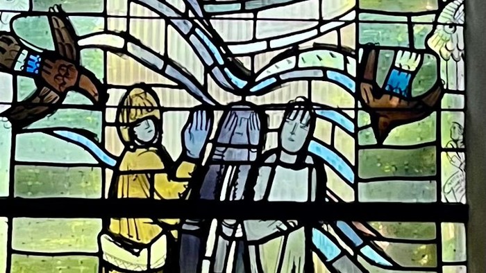 Das Bild zeigt ein buntes Kirchenfenster mit religiösen Motiven