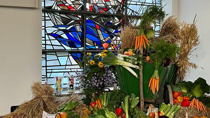 Bunte Gemüseauslage vor buntem Kirchenfenster