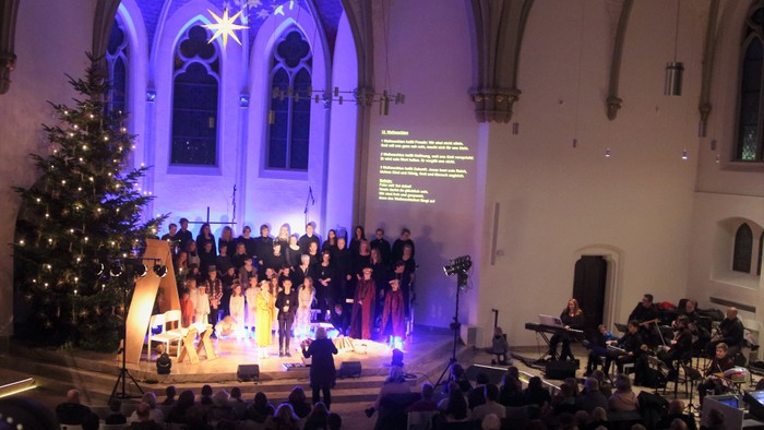 Große Kirche mit Weihnachtsbaum und Chor, viele Menschen