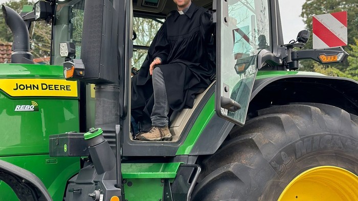 Mann sitzt in grünem John Deere Traktor