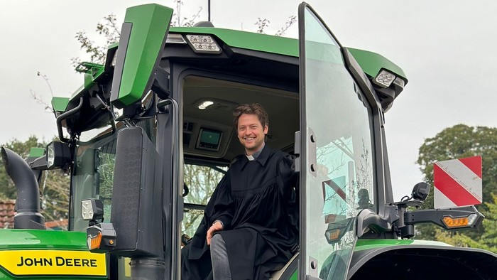 Mann sitzt in grünem John Deere Traktor
