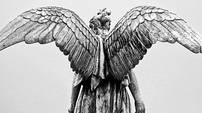 En svart og hvid statue af en vinged figur.