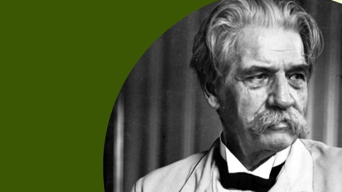 Albert Schweitzer sitzt und schaut seitlich an der Kamera vorbei.
