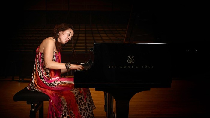 En kvinde spiller piano på scenen.