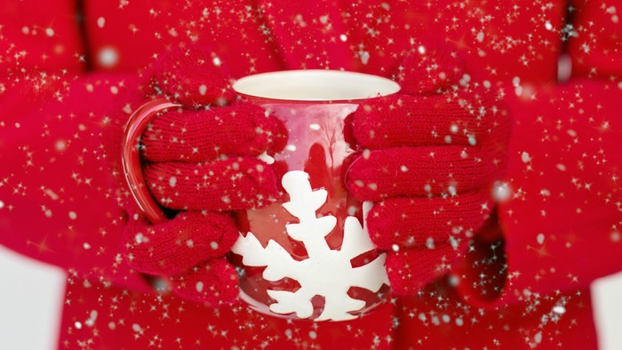 Person in rotem Mantel hält Tasse mit Schneeflockenmuster
