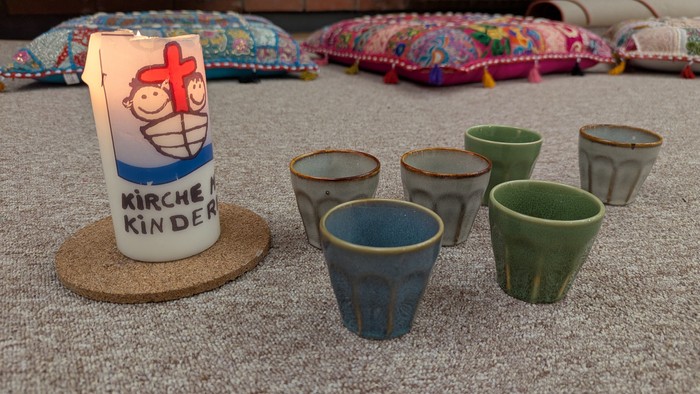 Kirchenkerzen und bunte Teelichter auf einem Tisch