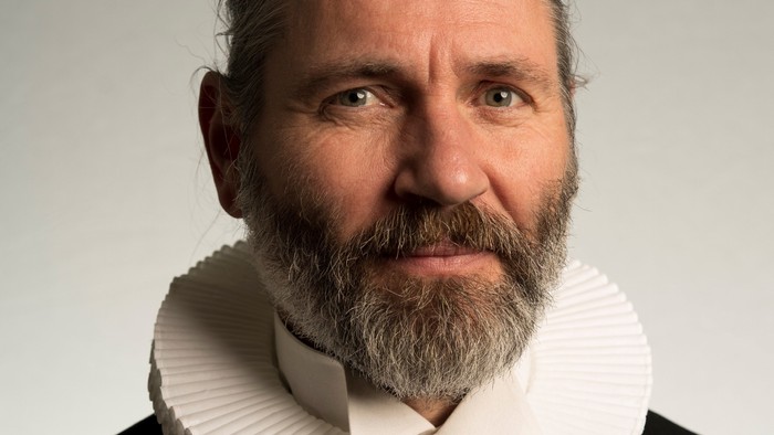 En bart og langhåret mand i historisk klædedrakter.