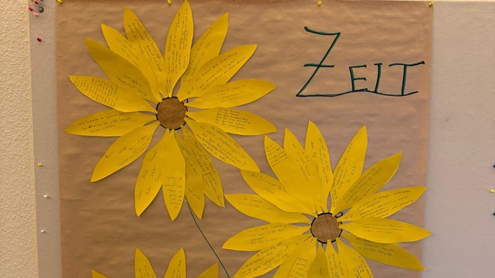 Bild zeigt drei gelbe Blumen mit dem Wort