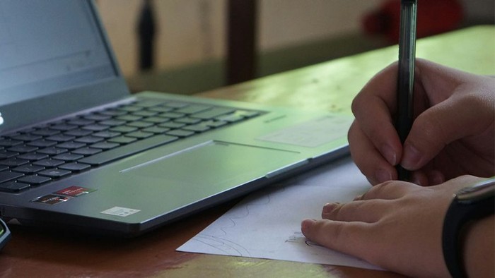 Offener Laptop, Person schreibt auf Zettel