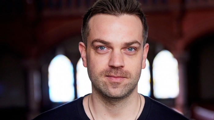 Frederic Riedel steht in der Apostel-Paulus-Kirche vor den Seitenfenstern.