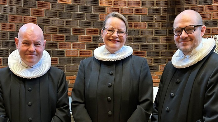Tre præster står sammen i kirke.