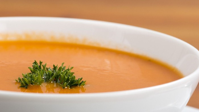 Eine Schale Suppe mit Thymian auf einem Holztisch