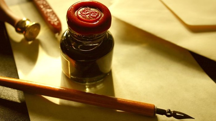 Ein Tintenfass mit Siegel und Feder auf einem Tisch