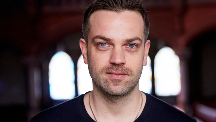 Frederic Riedel steht in der Apostel-Paulus-Kirche vor den Seitenfenstern.