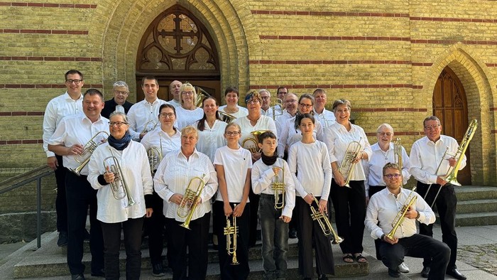 Ein Bläserensemble posiert vor einem Kirchenportal