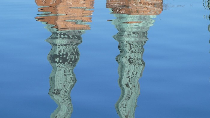 Zwei verzierte Säulen spiegeln sich im Wasser wider
