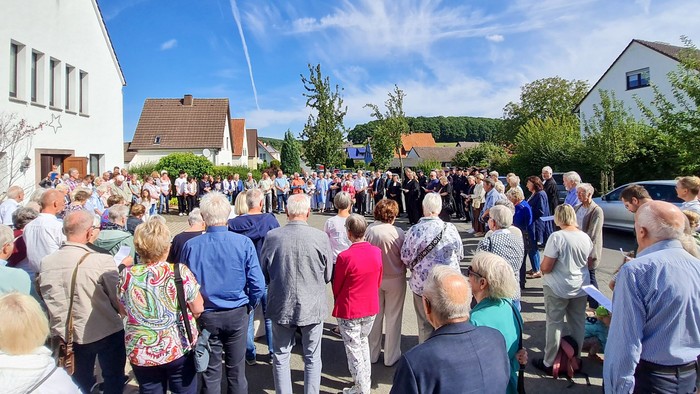 Eine Menschenmenge im Kreis im Freien vor der Jubilatekirche Bonneberg