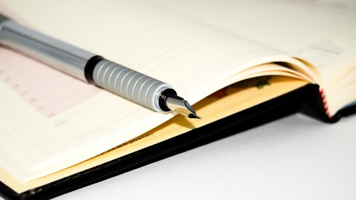 Ein silberner Füller liegt auf einem aufgeschlagenen Notizbuch.