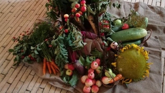 På kirkegulvet foran knæfaldet ligger der to gamle sække, hvorpå der er pyntet med alle mulige høstede frugter, korn og blomster.