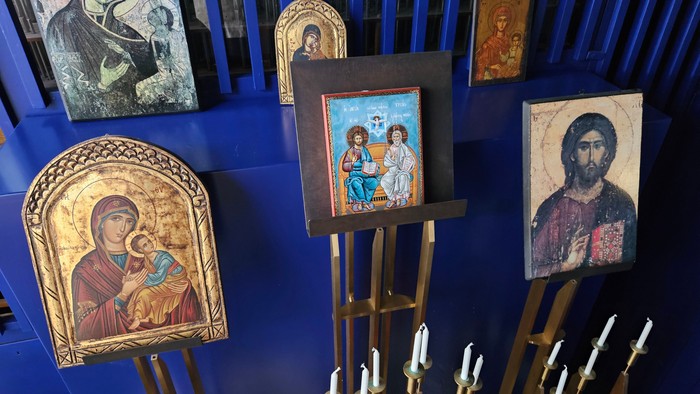 Billedet viser religiøse ikoner og lysstake i en kirke.