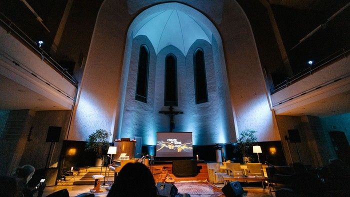 Ein Kircheninneres mit beleuchtetem Altar und Menschen.