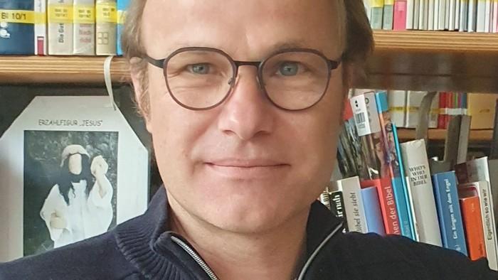Mann mit Brille vor Bücherregal