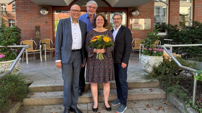 Drei Männer und eine Frau mit einem Blumenstrauß stehen vor dem Eingang des Seniorenheims Albestraße