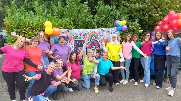 Das Team des Wichern-Kindergartens, dahinter ein Banner mit einer 50, Büsche und Luftballons