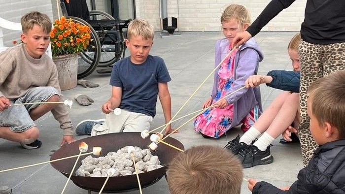 Børn spiser marshmallows med stokke.