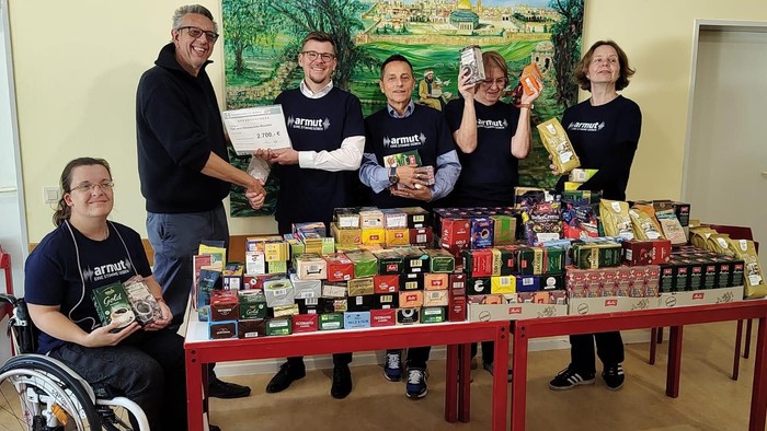 Tisch mit den Kaffeespenden des Jahres 2024; dahinter sehen Armutsbeauftragter Thomas der Vachroi und Unterstützer*innen