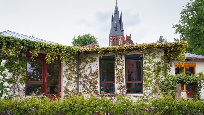 Ein Haus mit Efeu und einem Kirchturm im Hintergrund